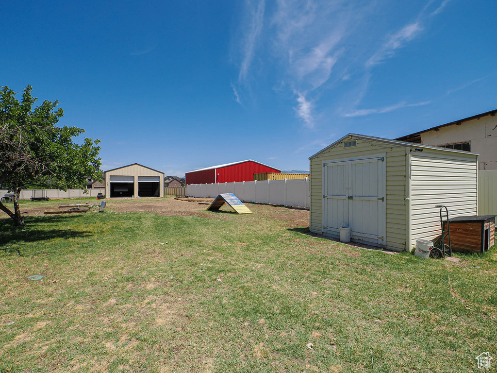 View of yard featuring a detached garage, a storage shed, and driveway