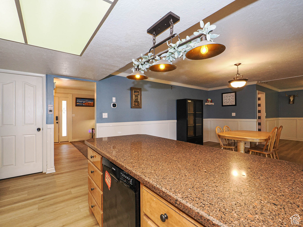 Kitchen featuring dishwasher, light wood-style flooring, a wainscoted wall, a textured ceiling, and stone counters