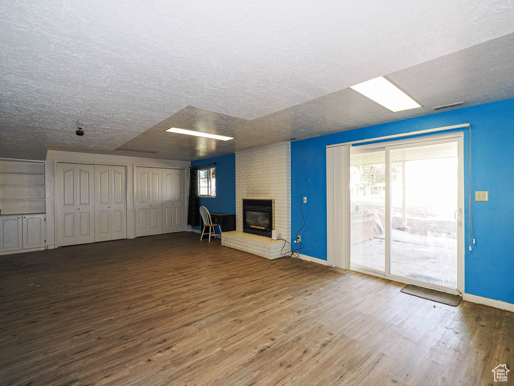 Unfurnished living room with wood finished floors, a fireplace, and a textured ceiling