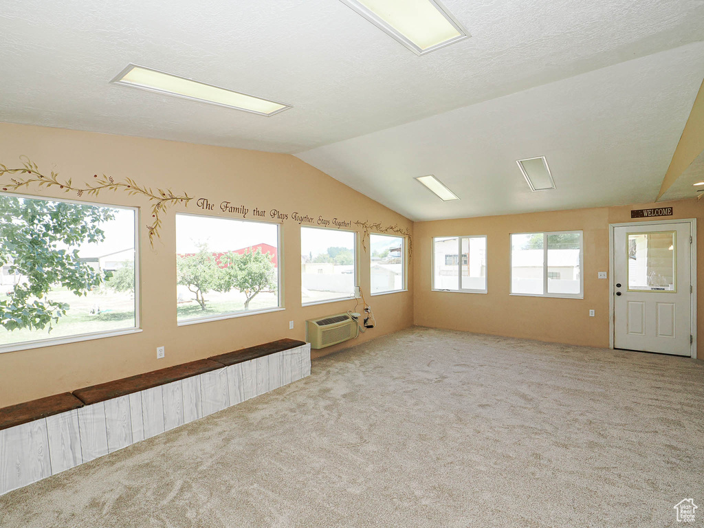 Spare room featuring carpet floors, lofted ceiling, and a wall mounted AC