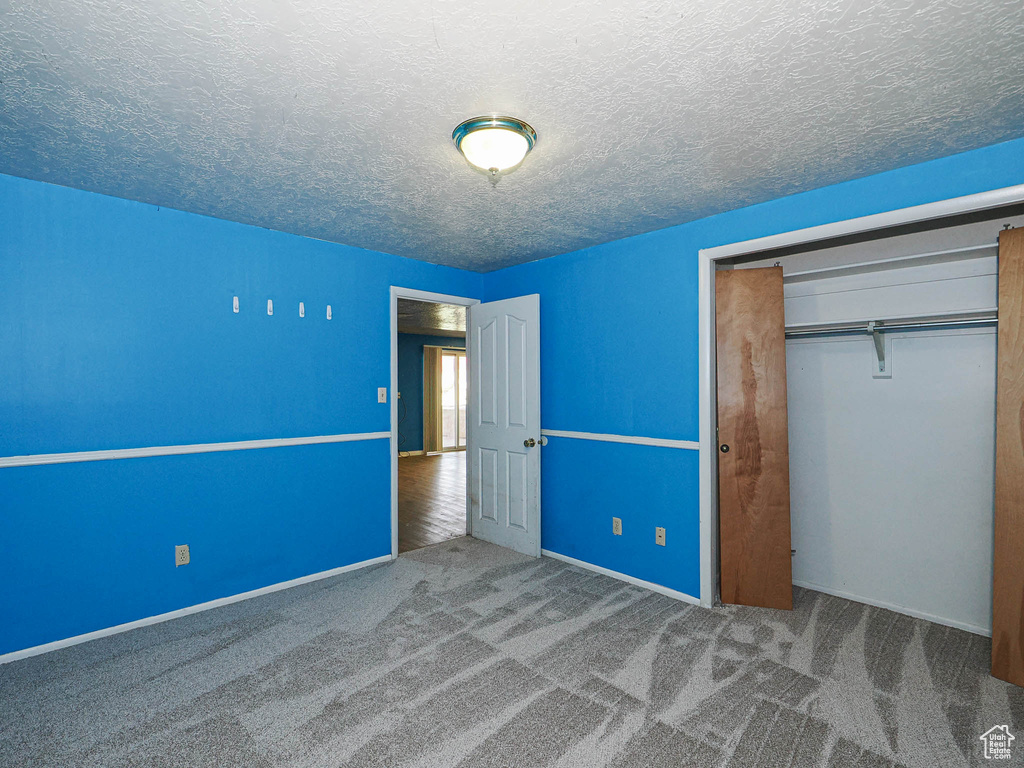 Unfurnished bedroom with a closet, carpet flooring, and a textured ceiling