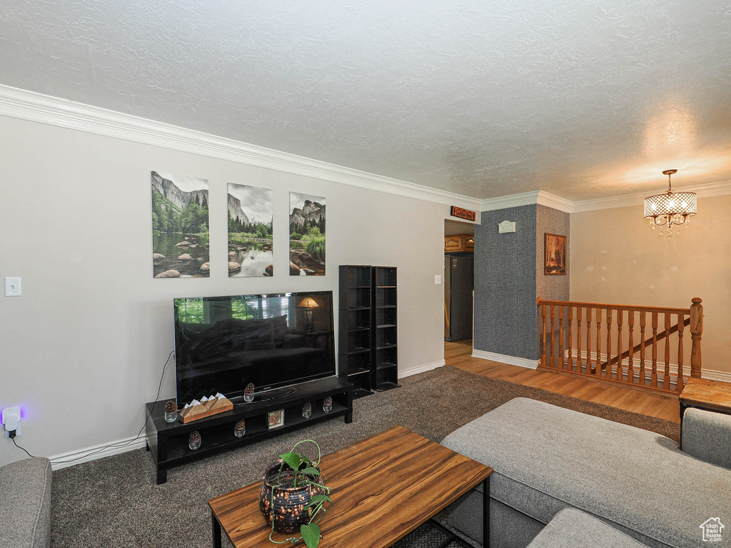 Living area featuring crown molding, a chandelier, a textured ceiling, and wood finished floors