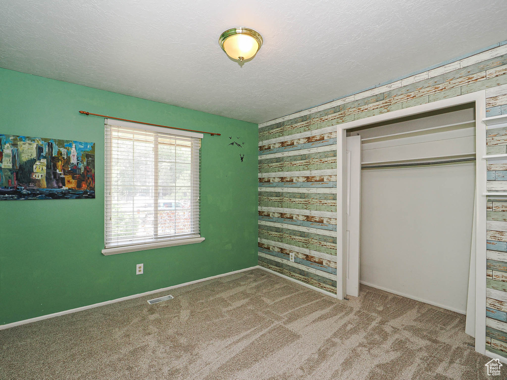 Unfurnished bedroom with carpet, a closet, and a textured ceiling
