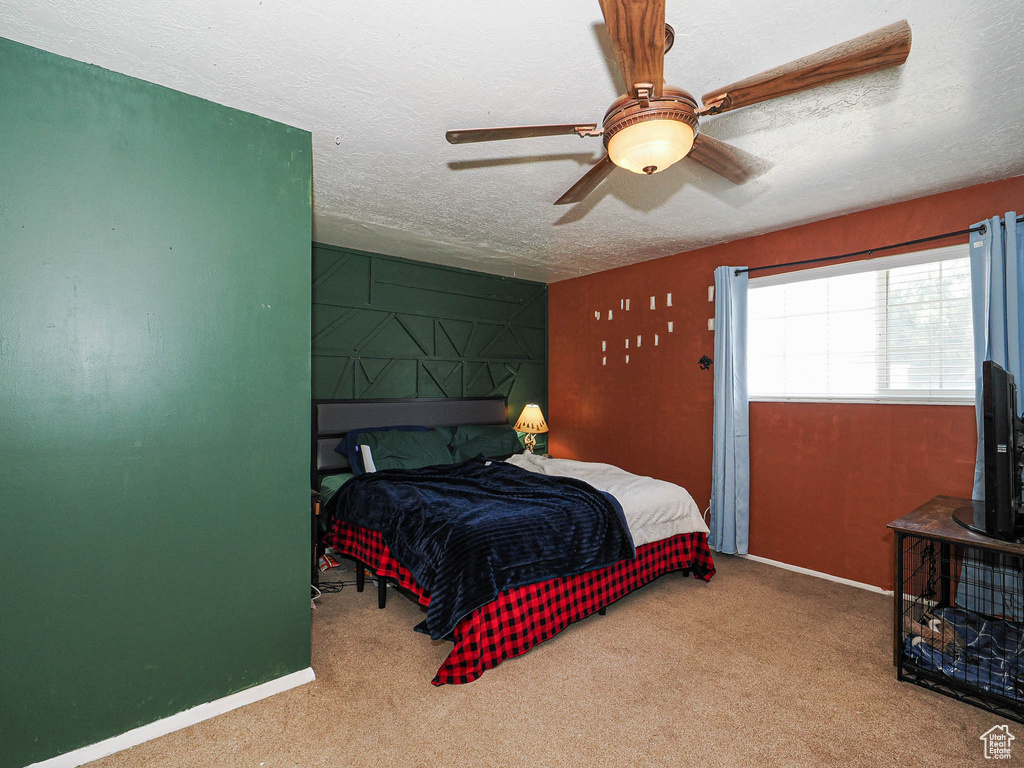 Carpeted bedroom featuring a textured ceiling and a ceiling fan