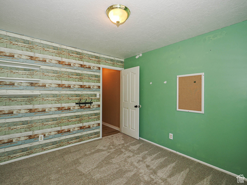 Carpeted spare room featuring a textured ceiling and baseboards