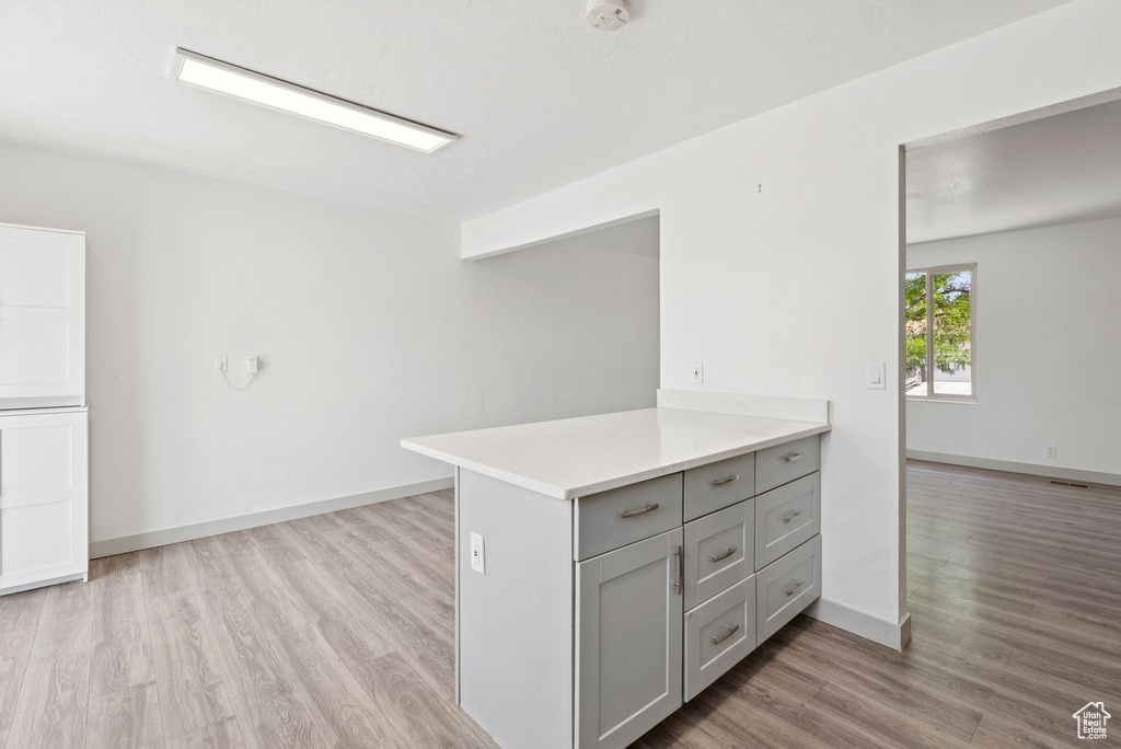 Kitchen with gray cabinetry, light wood-type flooring, and light countertops