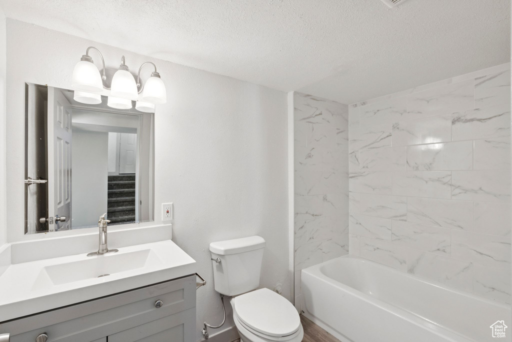Full bath featuring a textured ceiling, vanity, and  shower combination