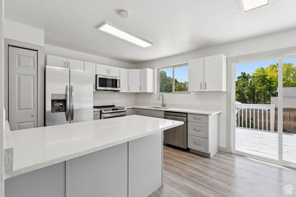 Kitchen featuring stainless steel appliances, light stone countertops, a peninsula, and gray cabinets