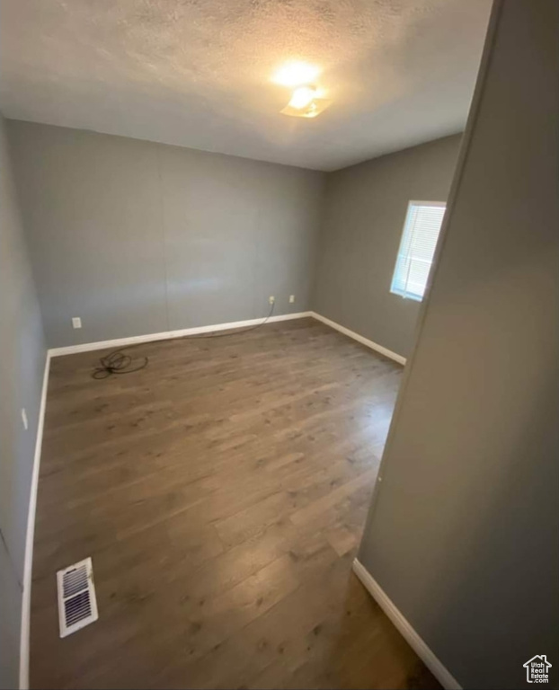 Spare room with wood finished floors and a textured ceiling