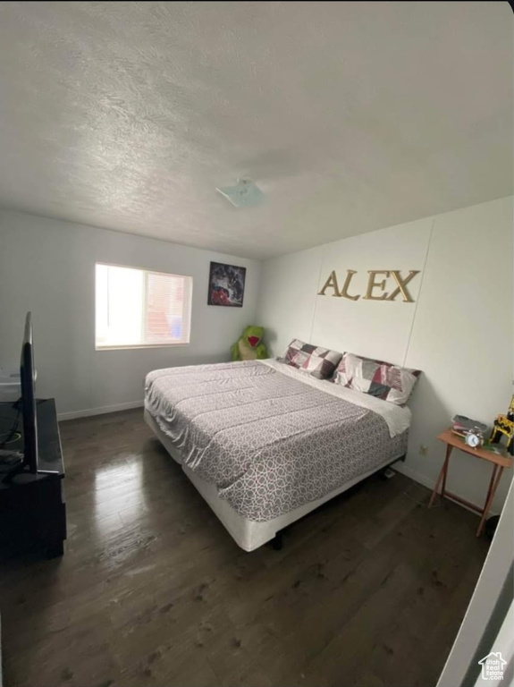 Bedroom with wood finished floors and a textured ceiling