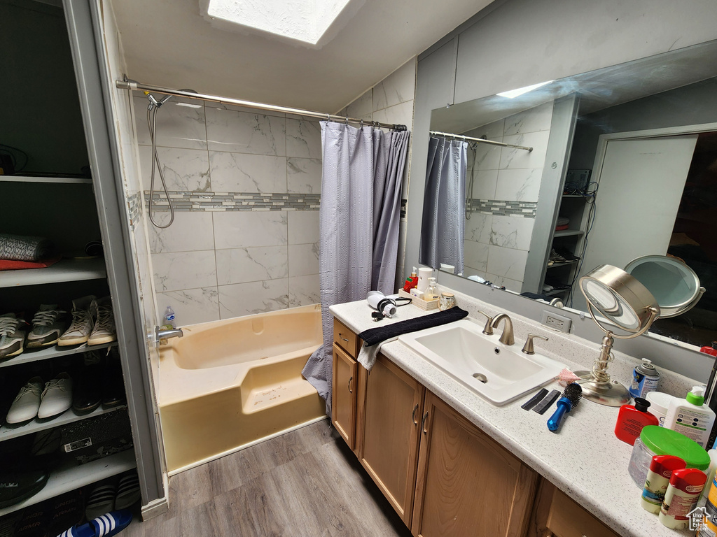 Bathroom featuring vanity, wood finished floors, and shower / bath combination with curtain