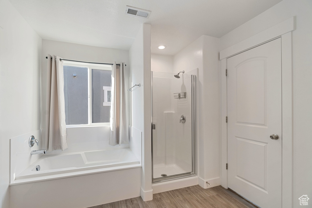 Bathroom featuring a shower stall, wood finished floors, a garden tub, and recessed lighting