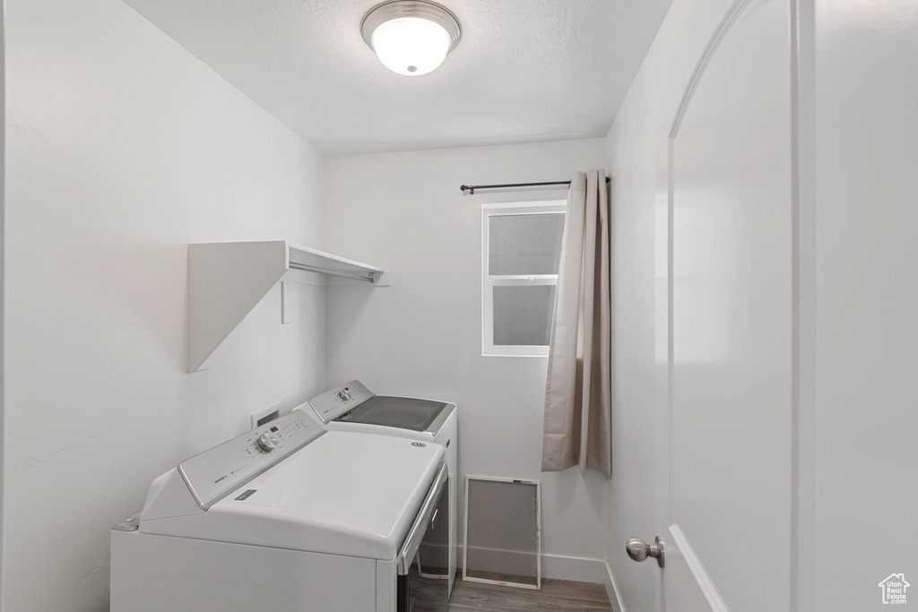 Washroom featuring washer and dryer, wood finished floors, and a textured ceiling