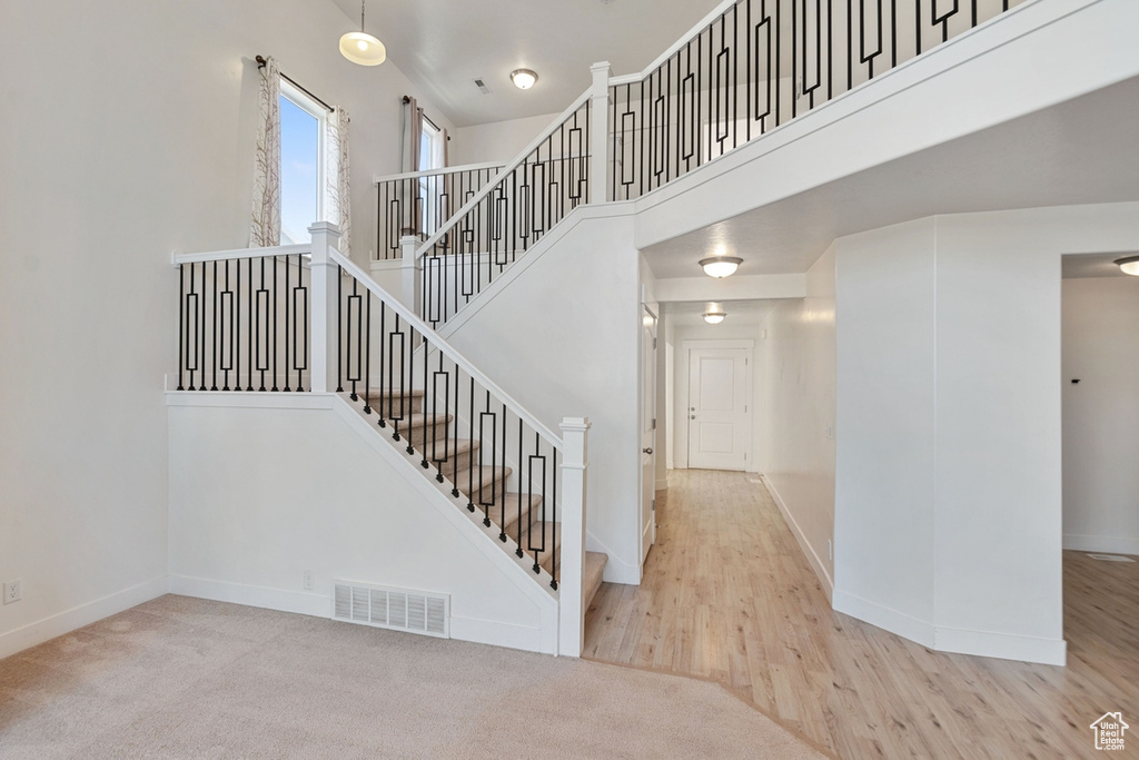Staircase with a towering ceiling and wood finished floors
