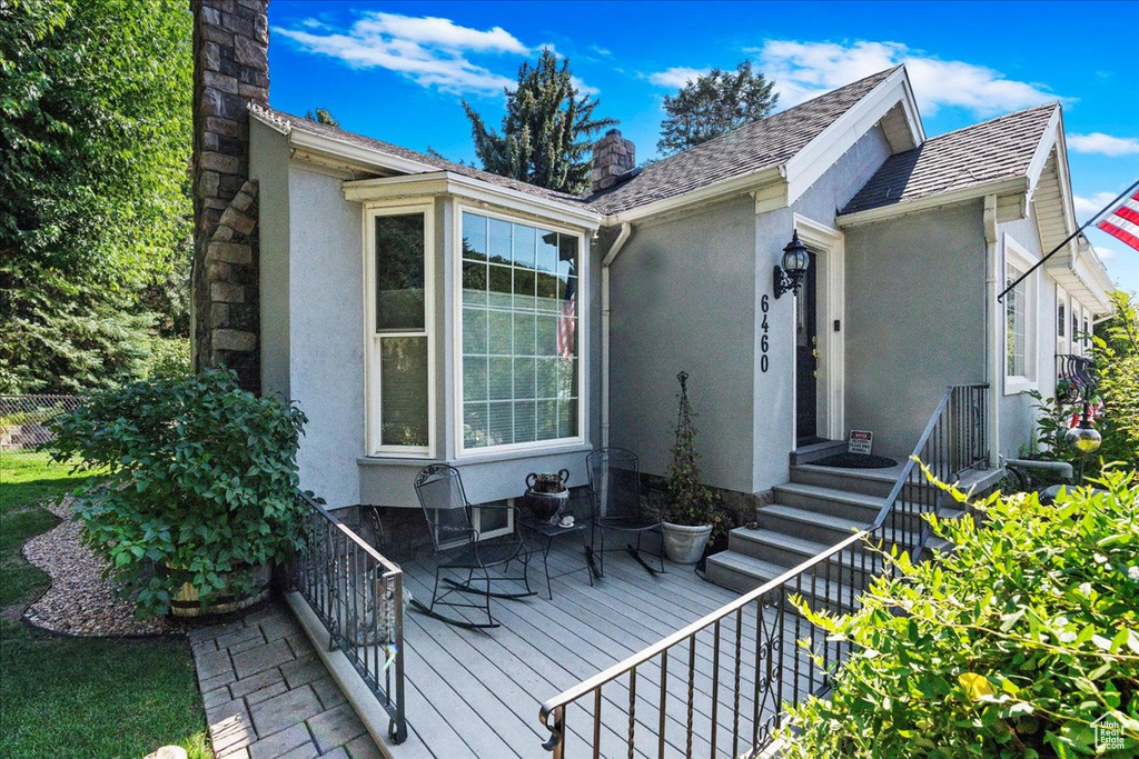 Doorway to property featuring stucco siding, a chimney, and a wooden deck