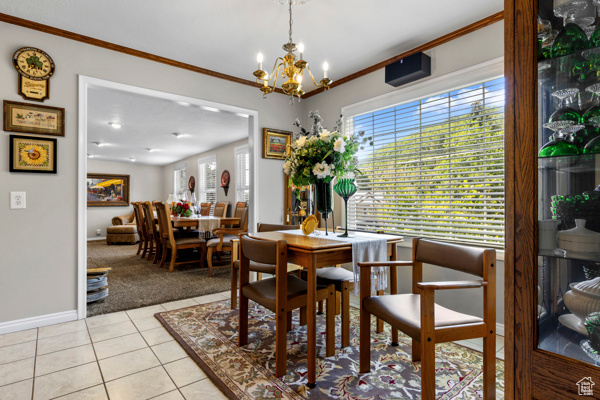 Dining space featuring a chandelier, light tile patterned floors, ornamental molding, and light carpet