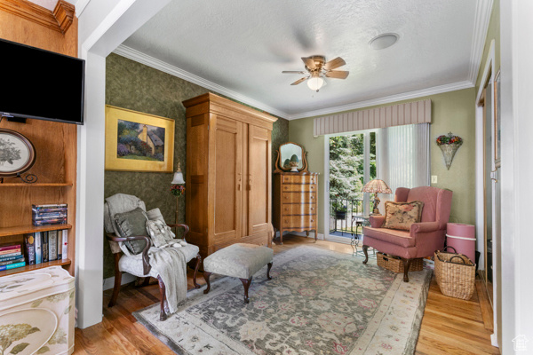 Living area with wood finished floors, a ceiling fan, and crown molding