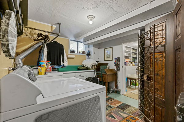 Washroom featuring washer and dryer, tile patterned floors, and a textured ceiling