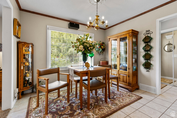 Dining area featuring a chandelier, ornamental molding, and light tile patterned flooring