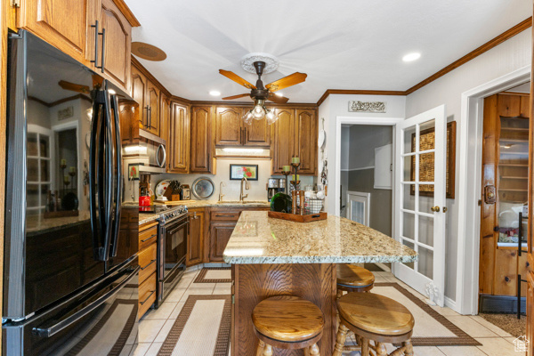 Kitchen featuring freestanding refrigerator, electric range, inlaid floor details, light tile patterned floors, and a ceiling fan