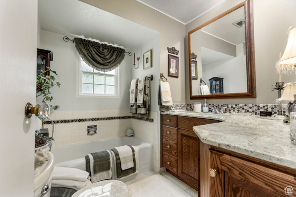 Full bath with vanity, a garden tub, and tile patterned flooring
