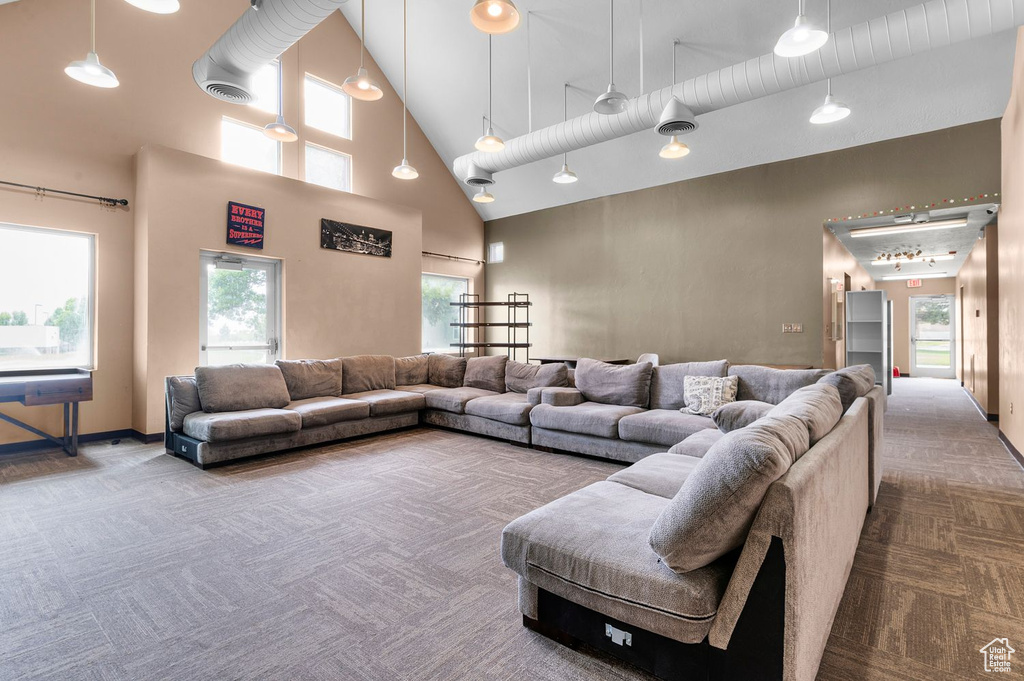 Carpeted living room with high vaulted ceiling and plenty of natural light