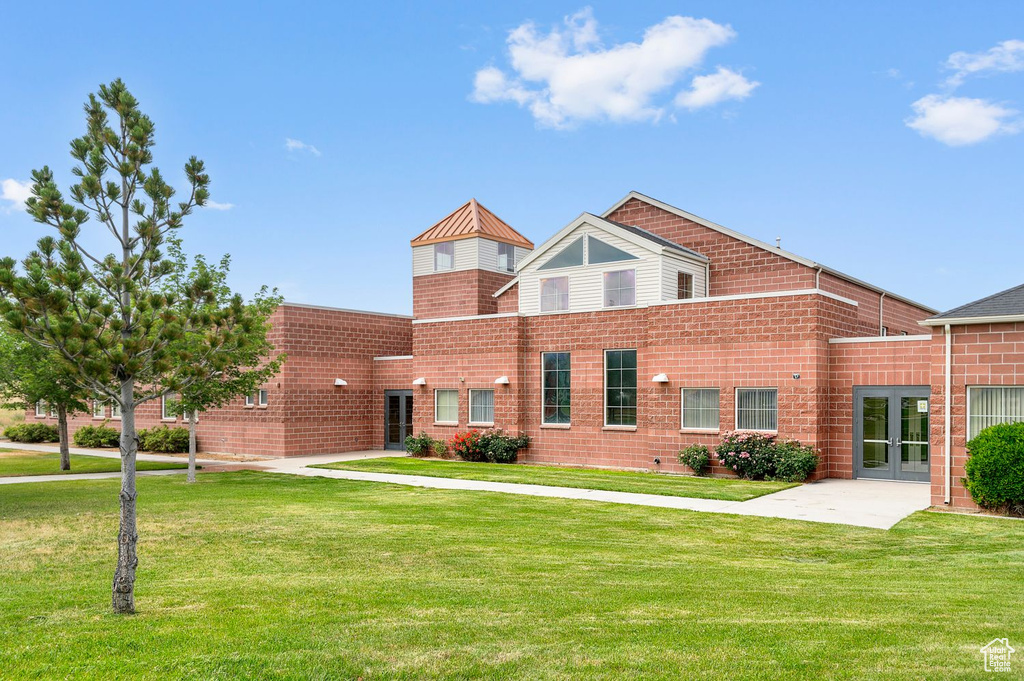 View of front of property featuring a front lawn, french doors, and brick siding