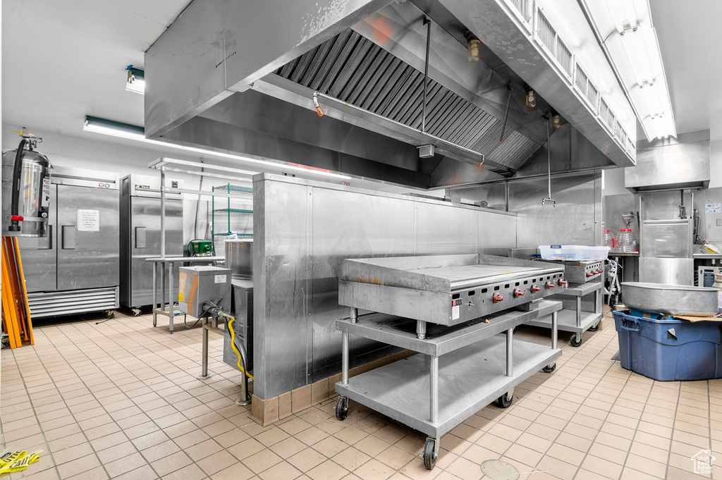 Kitchen with tile patterned flooring, custom exhaust hood, and refrigerator