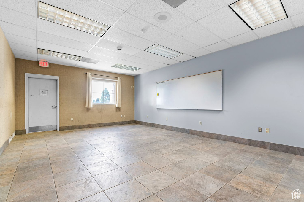 Empty room featuring a drop ceiling and baseboards