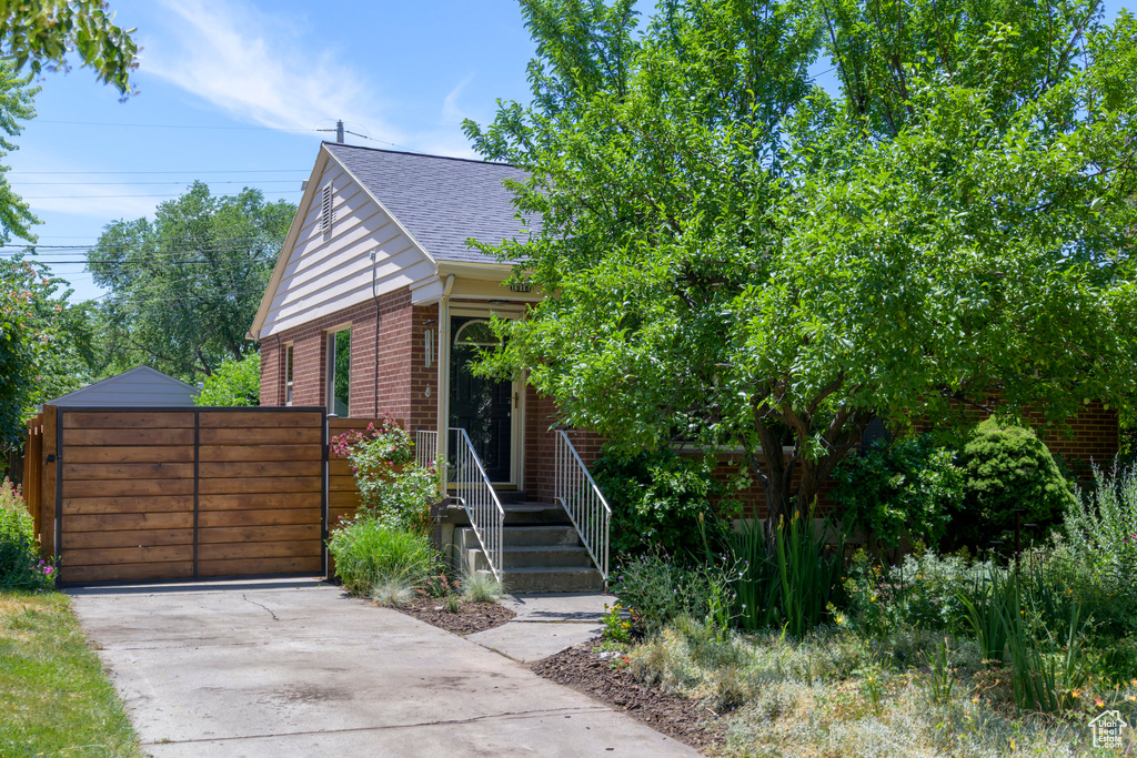 View of front of home featuring roof with shingles, brick siding, and driveway