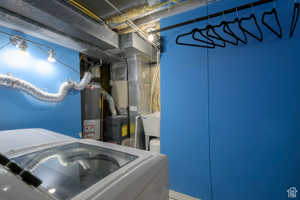 Unfinished below grade area featuring water heater, washer / clothes dryer, and heating unit