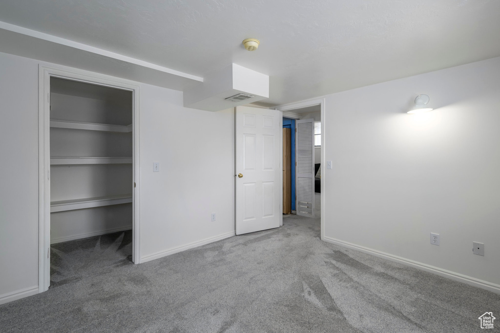 Unfurnished bedroom featuring carpet floors, a spacious closet, and a closet