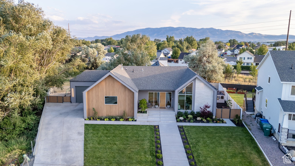 View of front of home with a mountain view, concrete driveway, and roof with shingles