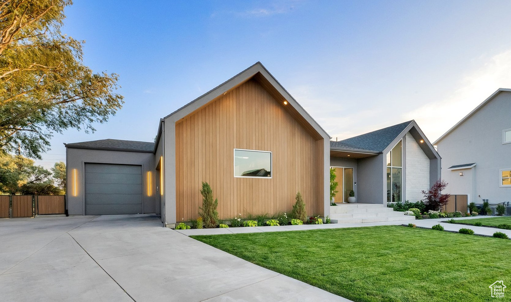 Contemporary home with concrete driveway, an attached garage, and a shingled roof