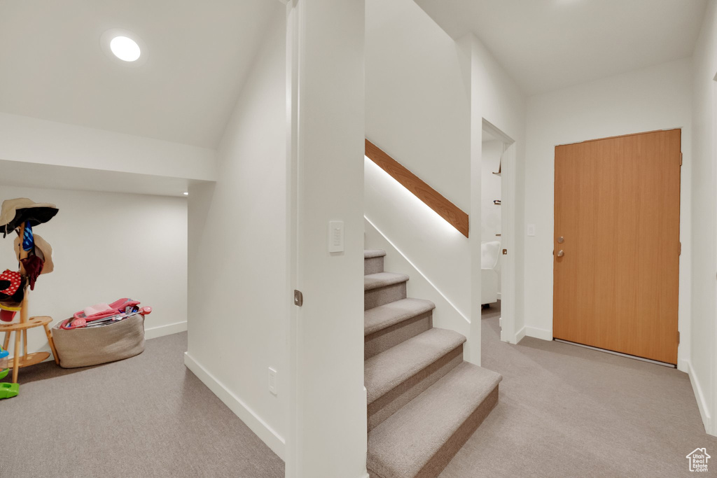 Carpeted entrance foyer with stairway and baseboards