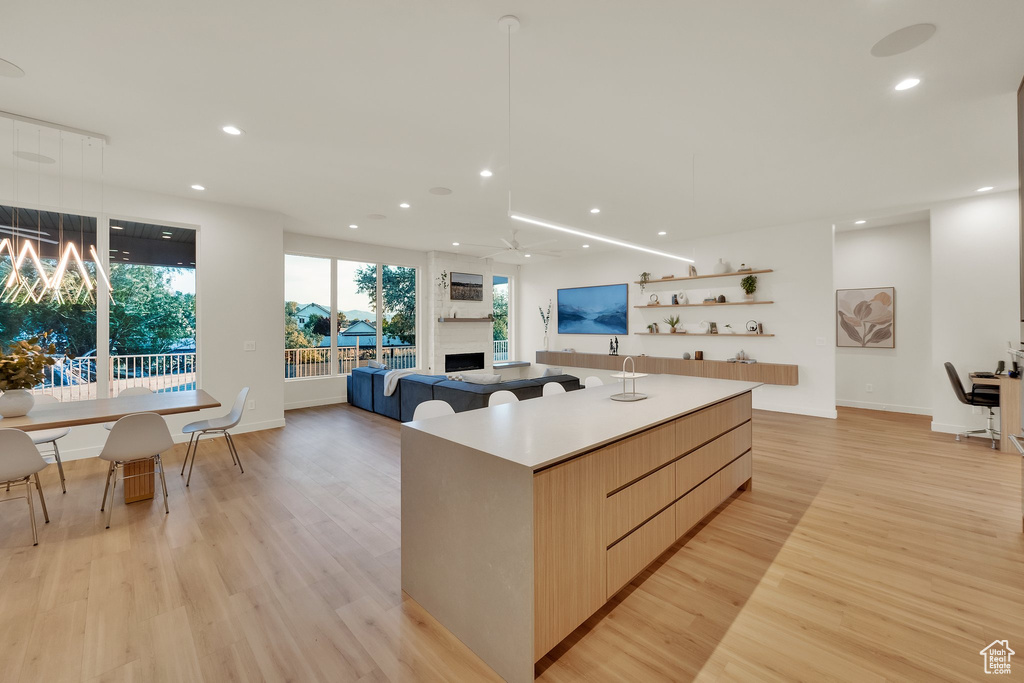 Kitchen with modern cabinets, a fireplace, a center island, light wood-style flooring, and recessed lighting