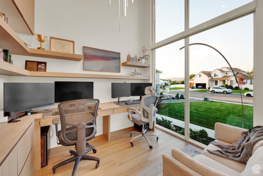 Office area with plenty of natural light, light wood-style flooring, built in desk, and a residential view