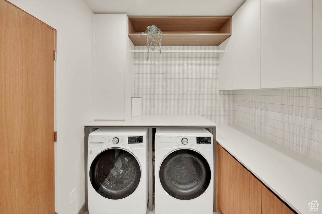 Laundry area featuring separate washer and dryer and cabinet space