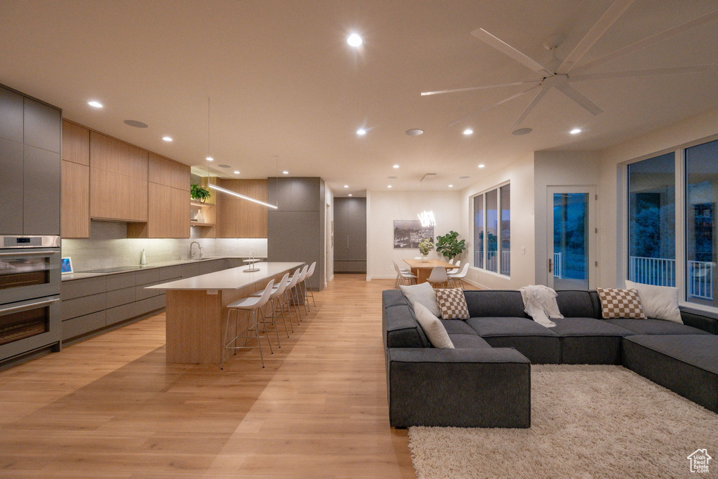 Living room with light wood finished floors, a ceiling fan, and recessed lighting