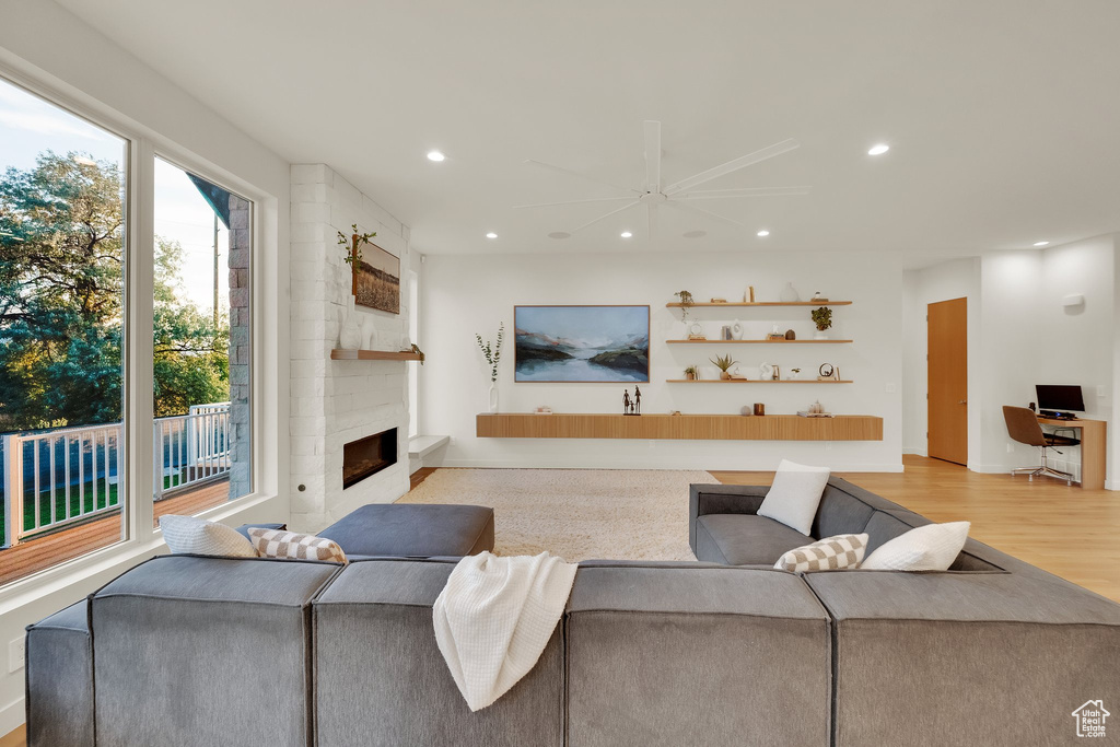 Living area with recessed lighting, a ceiling fan, a large fireplace, and light wood finished floors