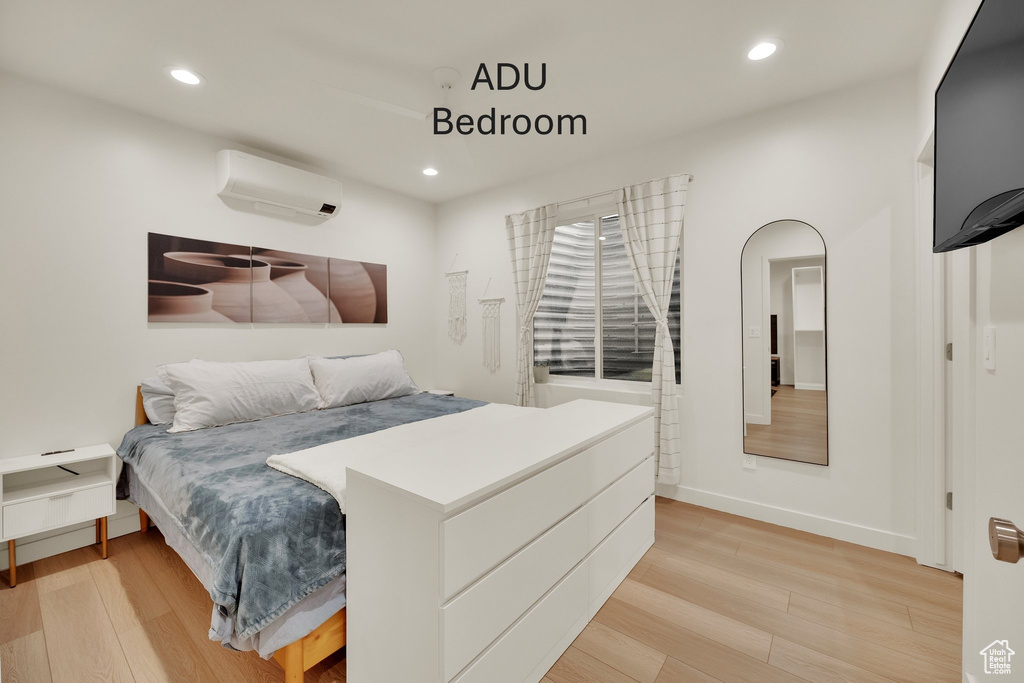 Bedroom featuring a wall mounted air conditioner, light wood-style flooring, recessed lighting, and arched walkways