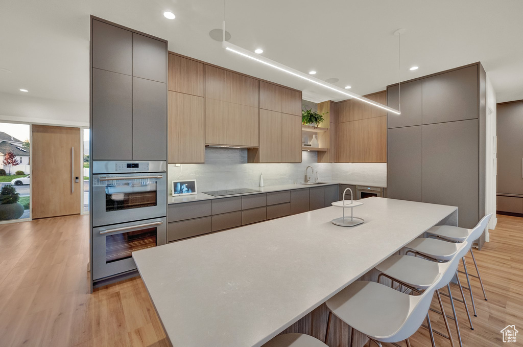 Kitchen with double oven, modern cabinets, open shelves, a breakfast bar, and recessed lighting