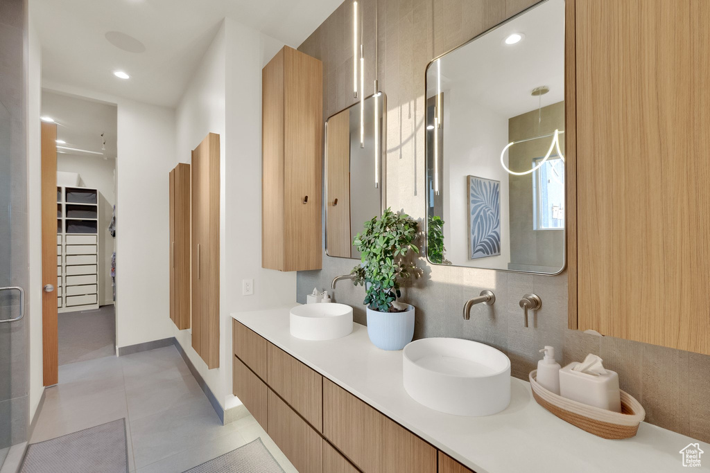 Full bath featuring double vanity, recessed lighting, tile patterned floors, and a walk in closet