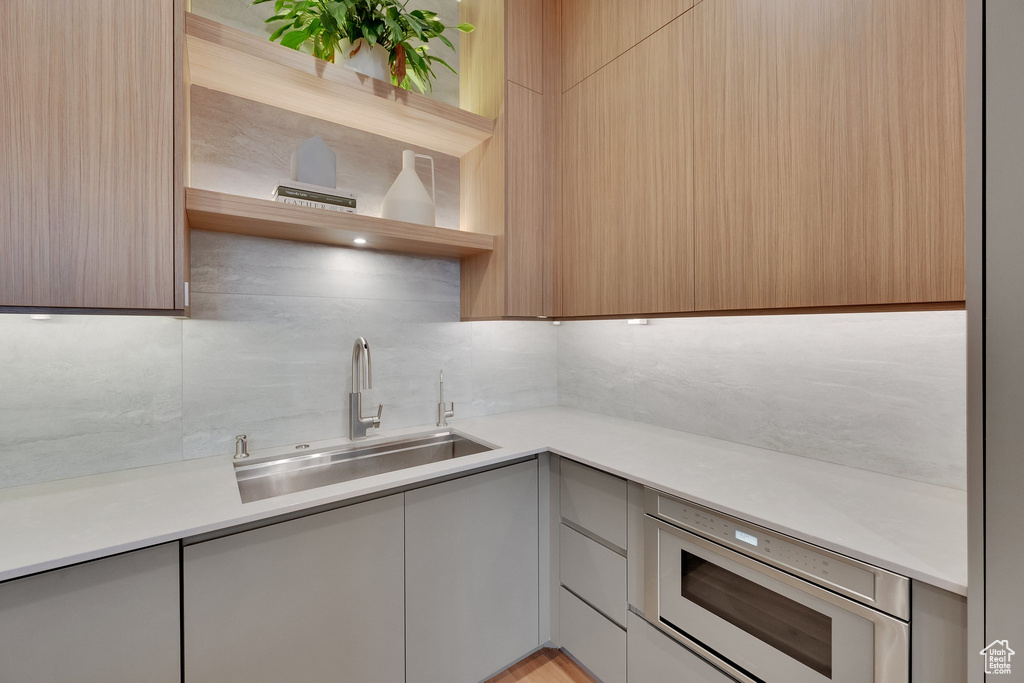 Kitchen with open shelves, modern cabinets, backsplash, and light countertops
