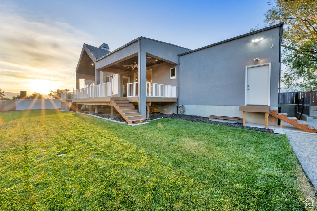 Back of house at dusk with stairway, ceiling fan, a deck, and stucco siding