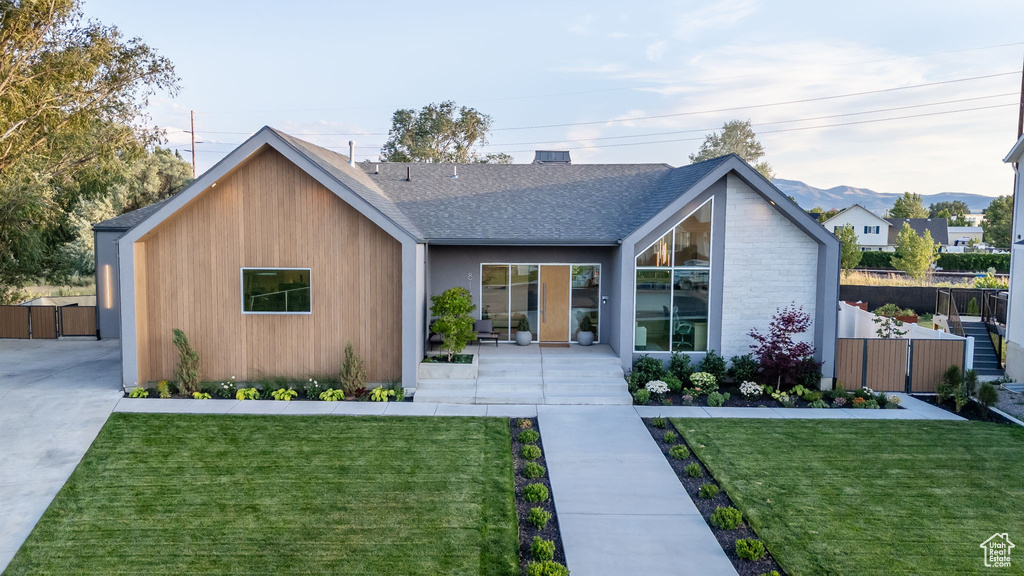 View of front of house with a gate, a shingled roof, and a mountain view