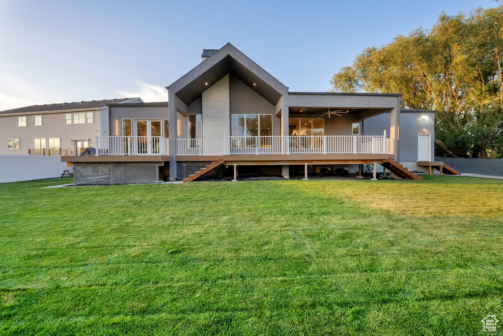 Back of house with stairway, a wooden deck, and stucco siding