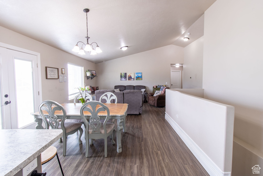 Dining space featuring dark wood-style flooring, lofted ceiling, and a chandelier