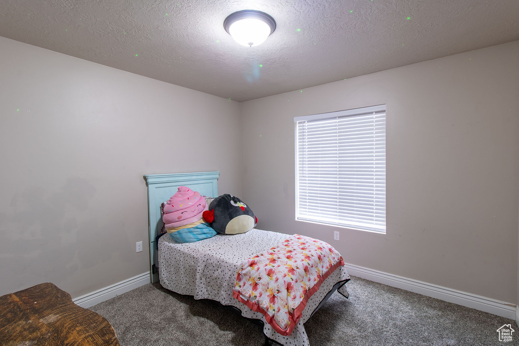 Carpeted bedroom with baseboards and a textured ceiling