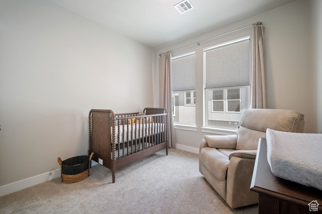 Bedroom featuring carpet flooring and a crib